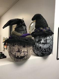 two black witches hats sitting on top of a white shelf next to a mirror and clock