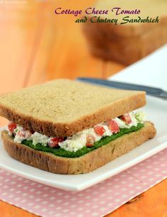 a sandwich is sitting on a plate next to a knife and some bread with cream cheese