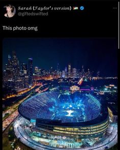 an aerial view of a stadium at night with the lights on and buildings in the background