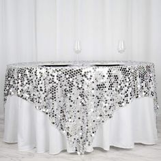 a table covered in sequins and wine glasses on top of a white table cloth