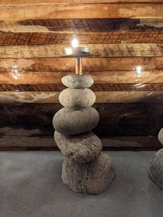 two rocks stacked on top of each other in front of a wall with a lamp