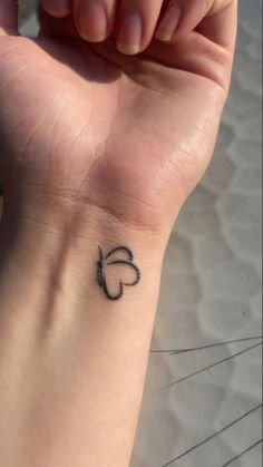 a small black heart tattoo on the wrist