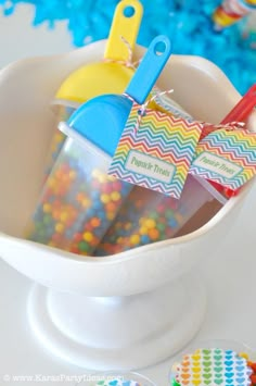 a cup filled with colorful candy and plastic spoons