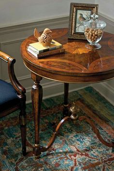 a wooden table with a glass vase on top of it next to a blue chair