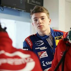 a young man in a racing uniform talking to someone