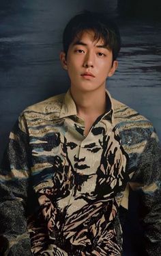 a young man standing in front of a dark background