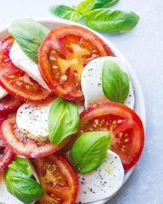 tomatoes, mozzarella and basil on a plate with text overlay that reads how to make caprese salad