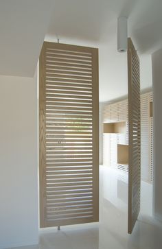 an empty room with wooden slats on the wall and white tile flooring in front of it