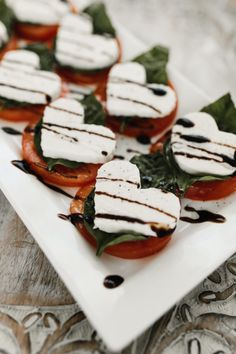 small tomatoes with mozzarella and spinach leaves on a white square platter