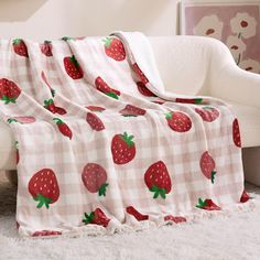 a blanket with strawberries on it sitting on a couch