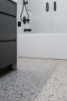 a bathroom with a bathtub, shower head and black faucet on the wall