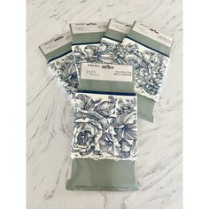 four blue and white floral napkins on a marble countertop with tags attached to them