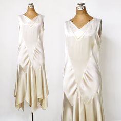 "Elegant vintage 20's silk satin wedding dress. Ivory bias cut dress has a classic twenties silhouette, sleeveless with a drop waist and godet skirt. Smocking at the hip and shoulder, handkerchief hem. Good condition, with very light staining at the underarms if closely inspected and a pindot stain on the skirt as shown in the last photo. A gorgeous vintage wedding dress perfect for a 1920's wedding.  MEASUREMENTS Bust: 35\" Waist: 32\" Hip: 37\" Length: 42\" - 46\" SIZE No Label Fits like Size Medium CONDITION GOOD - Wearable with minor imperfections To view more vintage dresses, follow the link below to my shop: https://www.MinkyVintage.etsy.com" 20s Drop Waist Dress, 1920s Chiffon Dress, 1930s Chiffon Dress, Vintage Off Shoulder Dress, 1920s White Dress, 1920s Drop Waist Dress, 1920s Skirts, 1920s Skirt, Flapper Wedding Dress