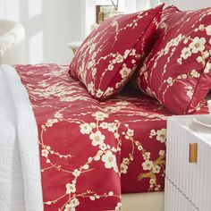 a bed with red and white floral bedspread, pillows and side tables in the background