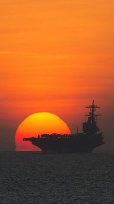 the sun is setting behind a large ship in the ocean with it's sails down