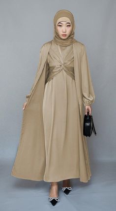 Introducing the Aigerim2 Piece Luxury Abaya from Annah Hariri, the epitome of sophistication and style. This stunning abaya set is crafted from high-quality satin fabric, ensuring both comfort and durability. The beige color exudes luxury and will leave a lasting impression wherever you go.The abaya features a maxi slip dress with maxi sleeves that provide full coverage and comfort. The wrap bodice adds a touch of elegance and femininity, while the elasticated cuffs offer a secure and snug fit. 2 Piece Abaya, New Abaya Style, Annah Hariri, Luxury Abaya, Fashion Kimono, Modest Activewear, Skirt Winter, Full Coverage Swimsuit, Abaya Style