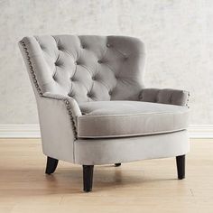 a gray chair sitting on top of a hard wood floor next to a white wall