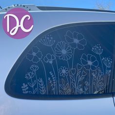 the back window of a car with flowers drawn on it's side and decals