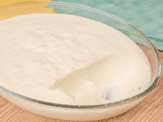 a bowl filled with white powder sitting on top of a wooden table next to a yellow towel