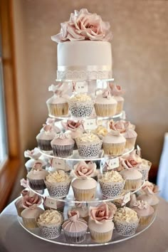 a three tiered cake with cupcakes on it