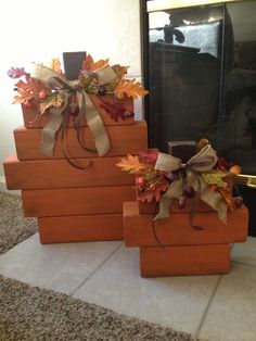 three wooden boxes with fall leaves and bows on them, sitting in front of a fireplace