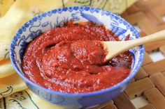 a blue bowl filled with red sauce on top of a wooden table next to a yellow napkin