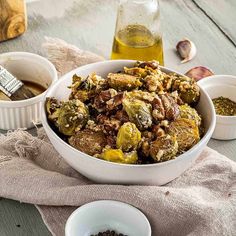 a white bowl filled with brussel sprouts next to two bowls of seasoning