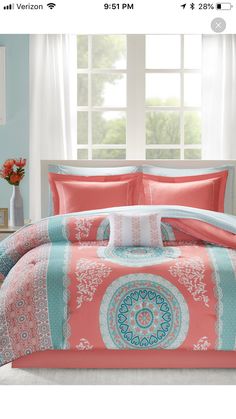 the comforter set is in coral and turquoise colors with an intricate medallion design on it