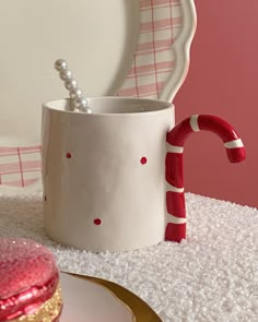 a cup with candy canes in it sitting on a table next to a plate