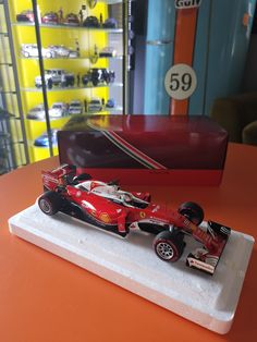 a red toy race car on display in a store with other model cars behind it