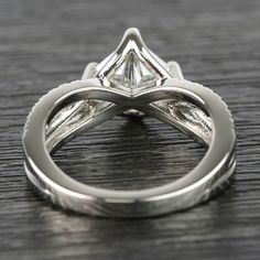 an engagement ring with a princess cut diamond in the center on a wooden table top