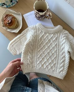 a person sitting at a table with a cup of coffee and a sweater on it