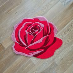 a red rose rug sitting on top of a wooden floor