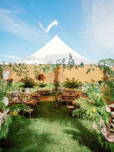 a large tent with tables and chairs in the grass