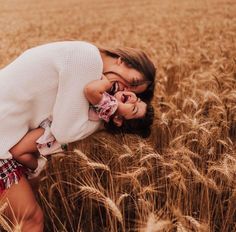 a woman and child are kissing in the middle of a wheat field