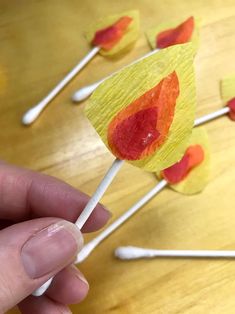 a hand holding a candy lollipop on top of a wooden table