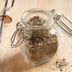 a glass jar filled with dirt sitting on top of a wooden table next to a pair of scissors