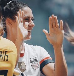 two female soccer players with their hands in the air