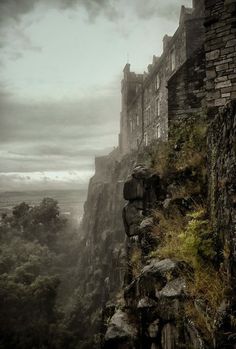 an old castle on the edge of a cliff with grass growing up it's sides