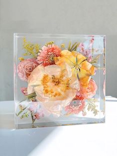 a clear box with flowers in it sitting on a table