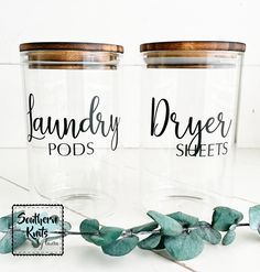 two clear jars with labels on them sitting next to each other