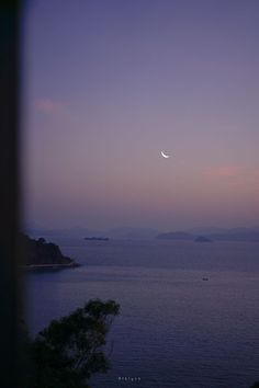 the moon is setting over the ocean and mountains