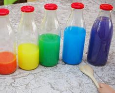 six bottles filled with different colored liquids on top of a table