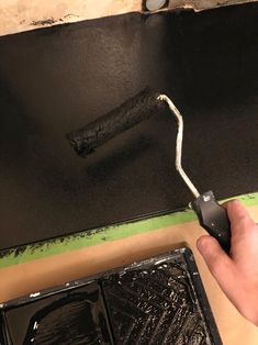 a man is painting the inside of a black piece of furniture with a paint roller