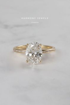 a close up view of a diamond engagement ring on a marble surface with the words harmony jewels