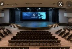 an empty auditorium with rows of seats and a projector screen