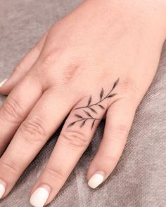 a woman's hand with a small black flower tattoo on the left ring finger