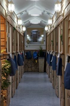 the hallway is lined with wooden walls and hanging bags on hooks, along with potted plants