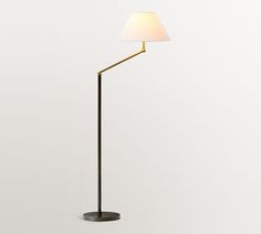 a floor lamp with a white shade on the base and a black metal pole that is holding a light bulb