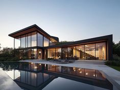 a large pool in front of a house with glass walls on the outside and inside